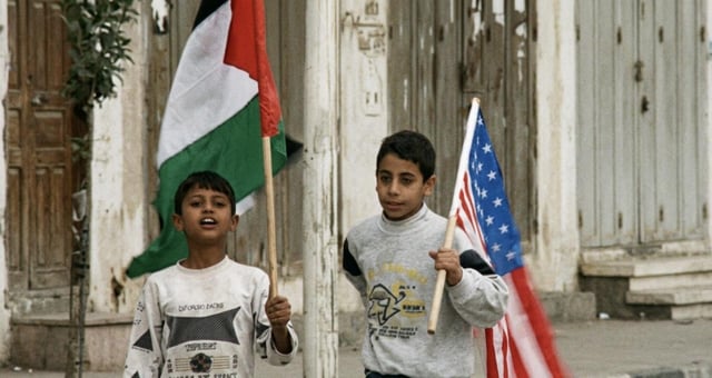 Two Palestinian boys holding US and Palestinian flags during Bill Clinton's visit to open Gaza International Airport, 1998 [1024x576]