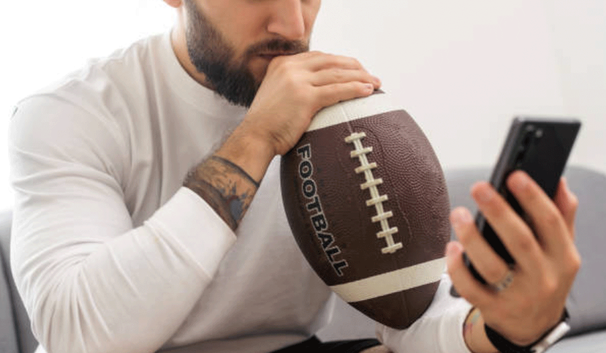 A Forty-Two-Year-Old Man Checks the Score of a High School Football Game